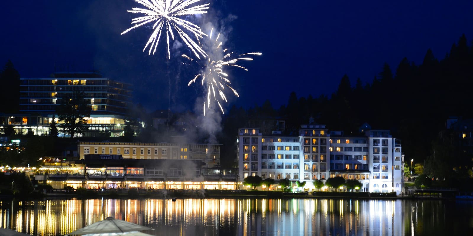Fireworks bursting over a lakeside village at night
